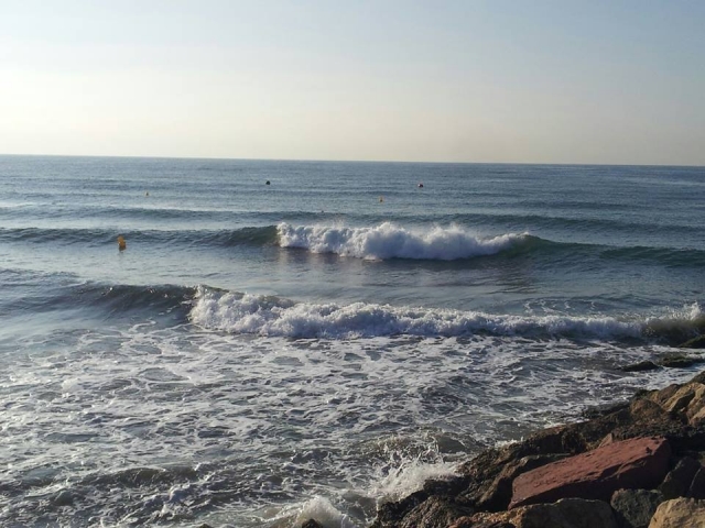 playa con pequenas olas y rocas en el lado derecho